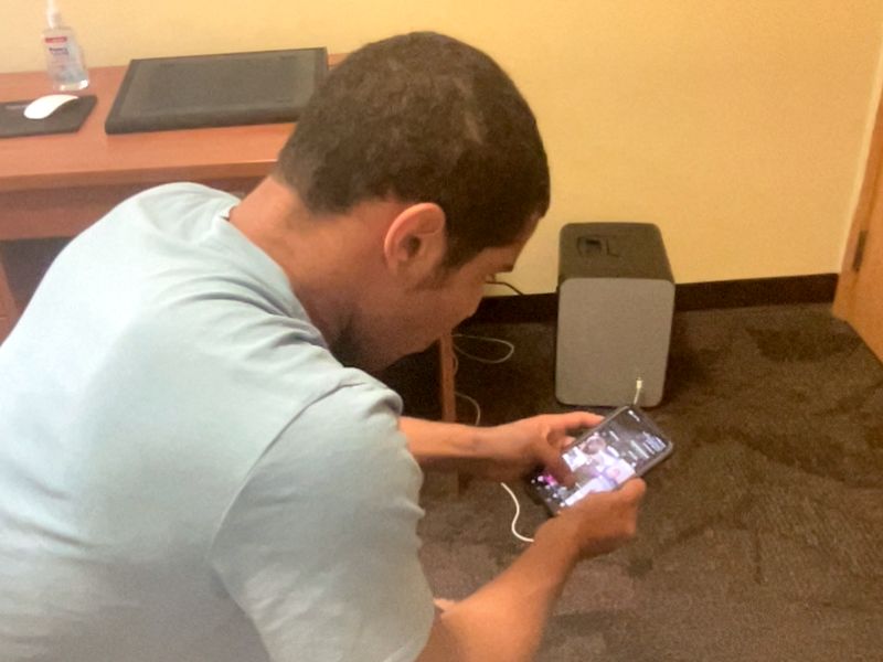 Aden looking at his phone while seated indoors.